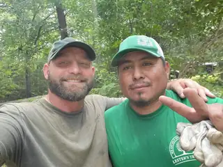 Two crew members squeezed into a selfie, one wearing a green Lester's shirt